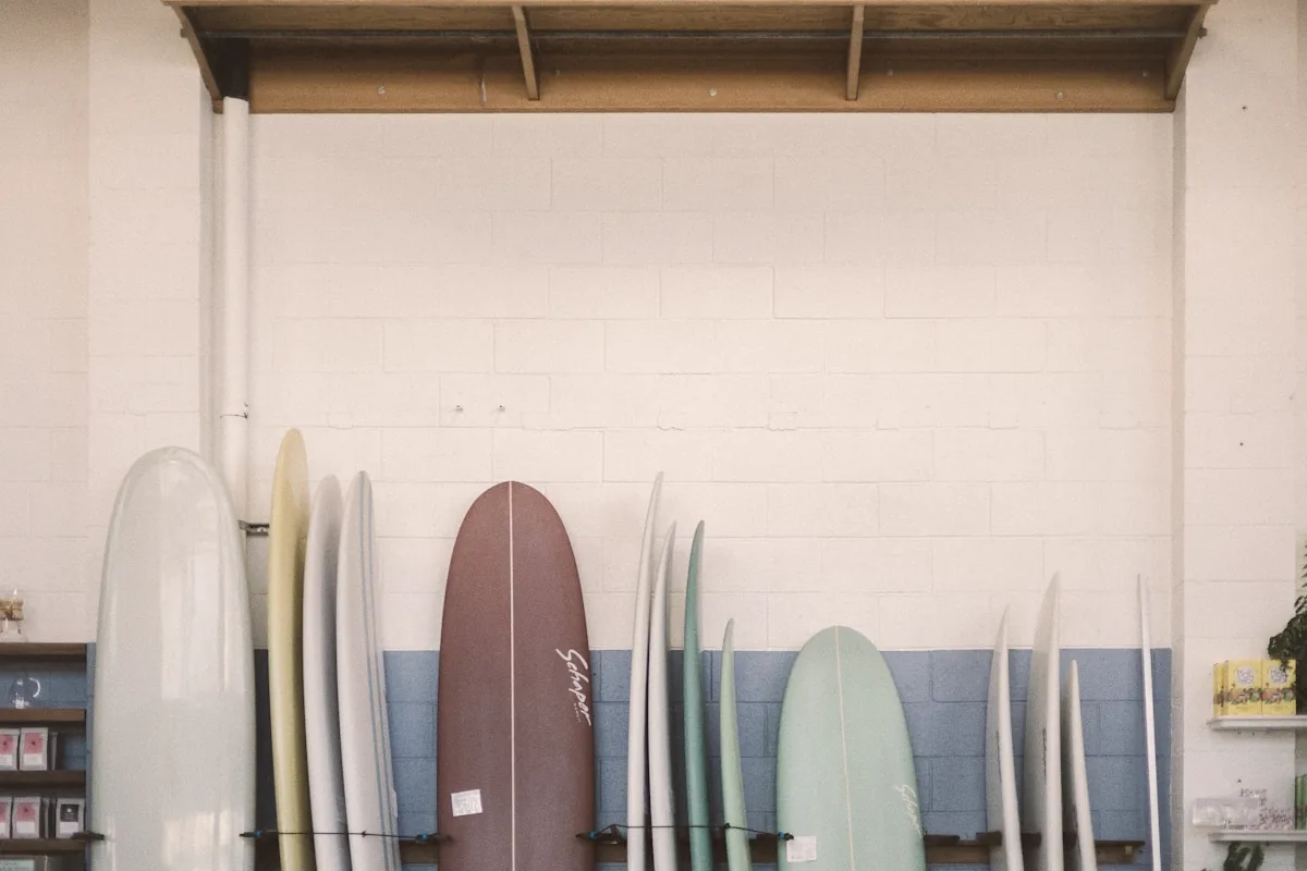 A quiver of surfboards standing in a row against a white wall